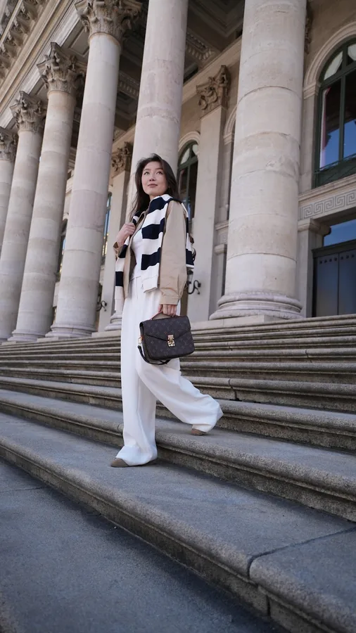 Full-length portrait in front of the Munich Nationaltheater portico.